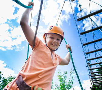boy holding onto ropes completing adventure challenge obstacles